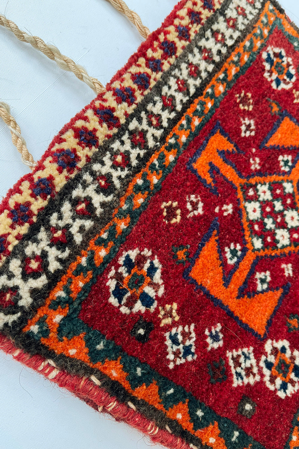 Vintage handgemaakte Perzische wollen zadeltas rood-oranje-beige-multi detail patroon - close-up van handgeknoopt tapijt