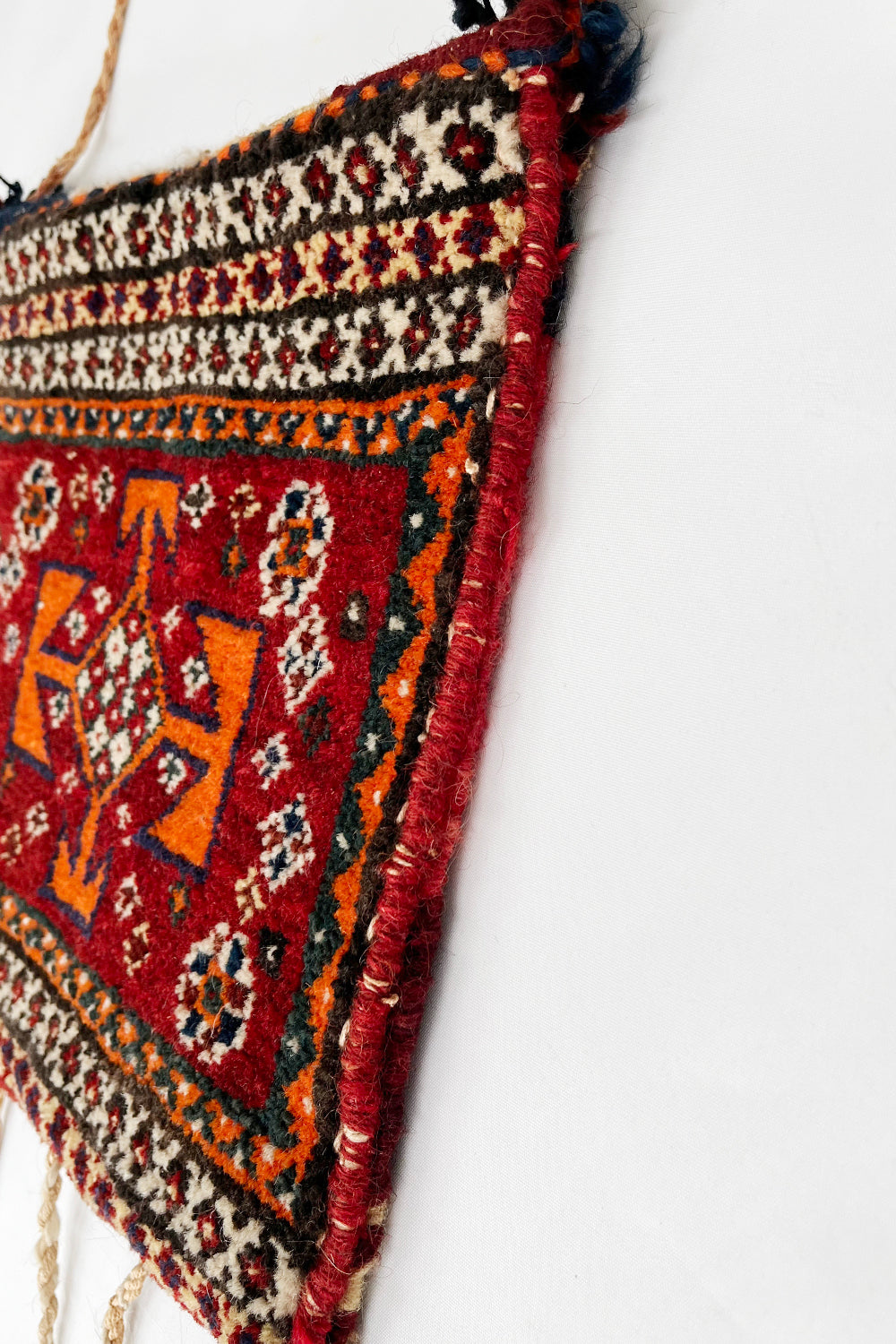 Vintage handgemaakte Perzische wollen zadeltas rood-oranje-beige-multi zijkant - kamelen tapijttas met franjes