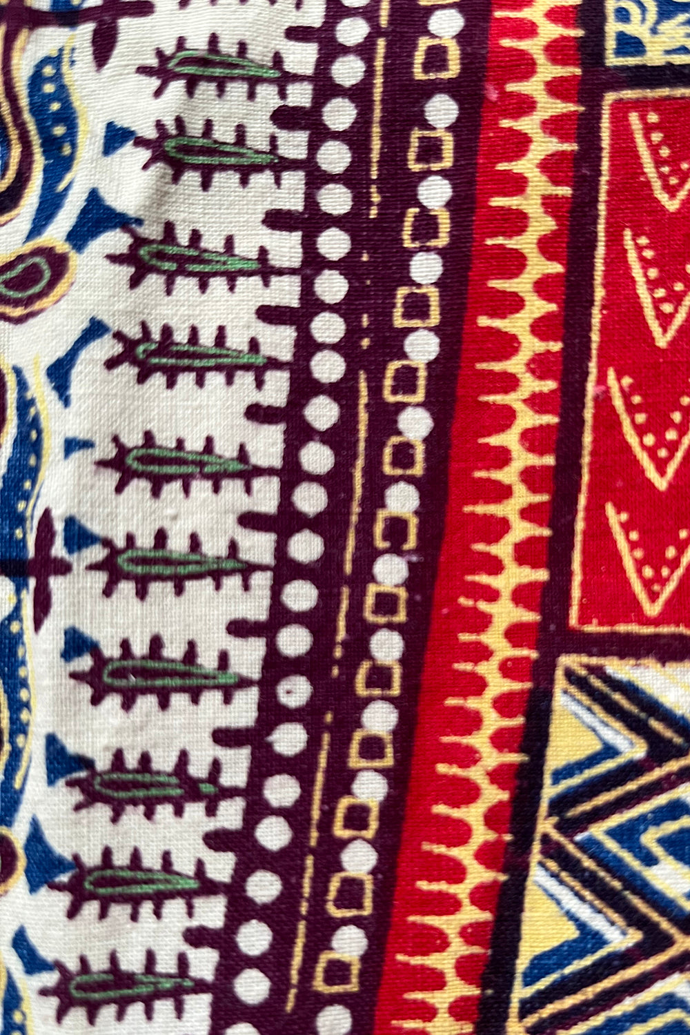 Close up stofstructuur vintage jaren 70 handgemaakte Dashiki tuniek in crème met kleurrijke print, katoenen top 