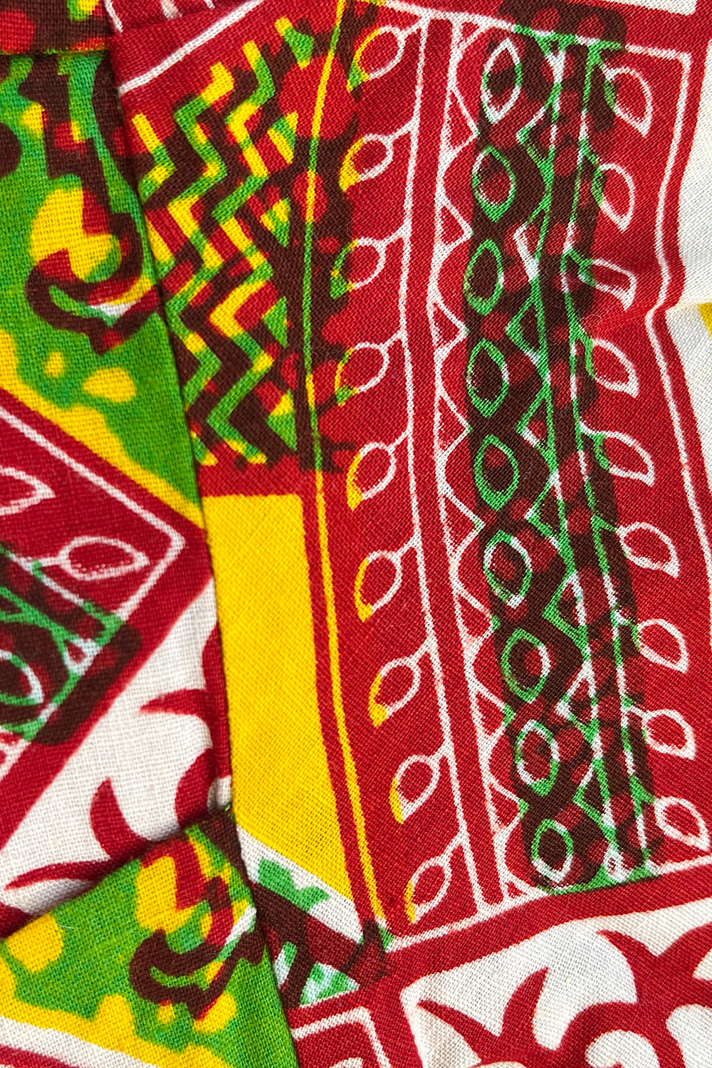 Vintage jaren 70 handgemaakte Afrikaanse batik peplum tuniek rood-groen-oranje-geel-wit detail - close-up van batik print 