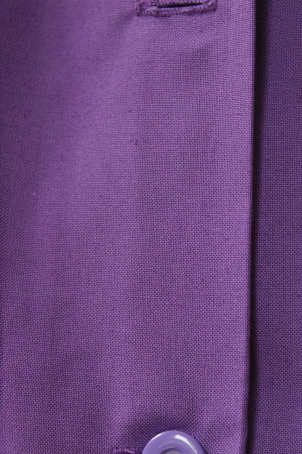 Close-up van de paarse geweven stof, het knoopsgat en de knopenlijst van het vintage werkschort.