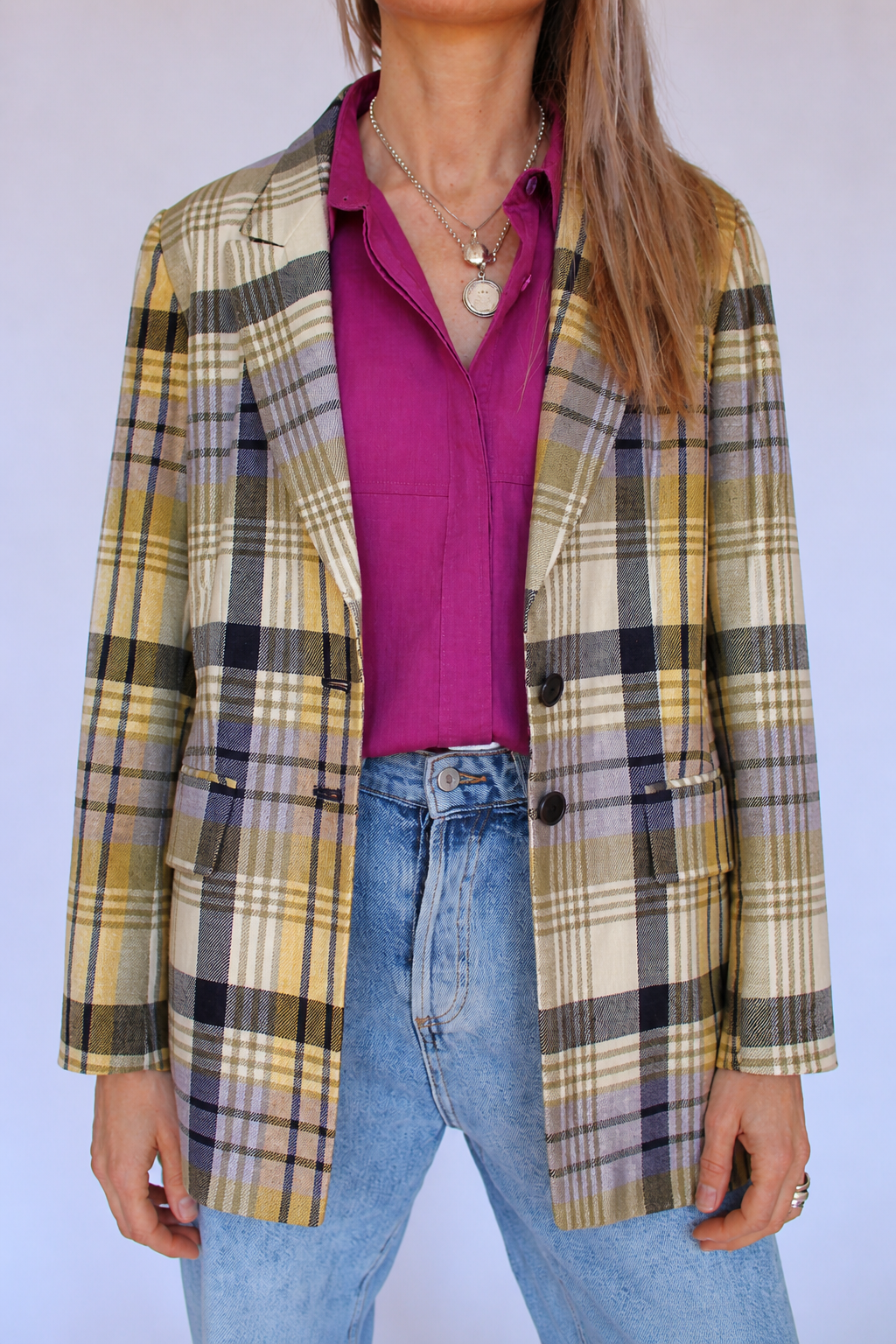 Vooraanzicht van de vintage Rena Lange blazer met ruiten in geel, beige, lila en zwart en twee donkere knopen.