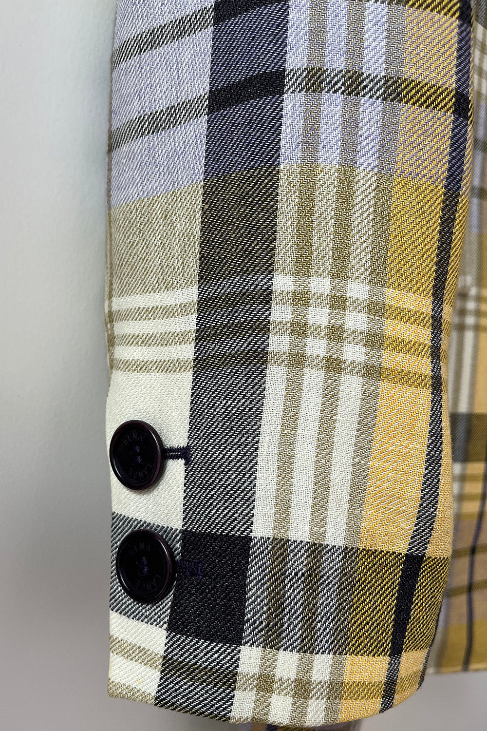 Detail van de geruite mouw met twee donkere manchetknopen van de blazer
