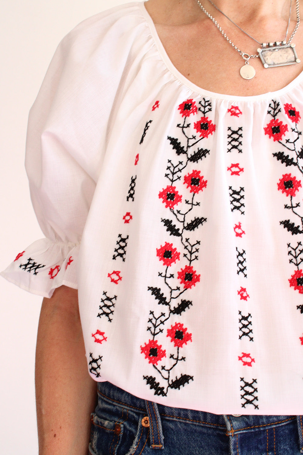 Vintage jaren 70 Bulgaarse geborduurde folklore bohemian blouse wit-multi detail mouw - close-up van rood en zwart borduurwerk pofmouw