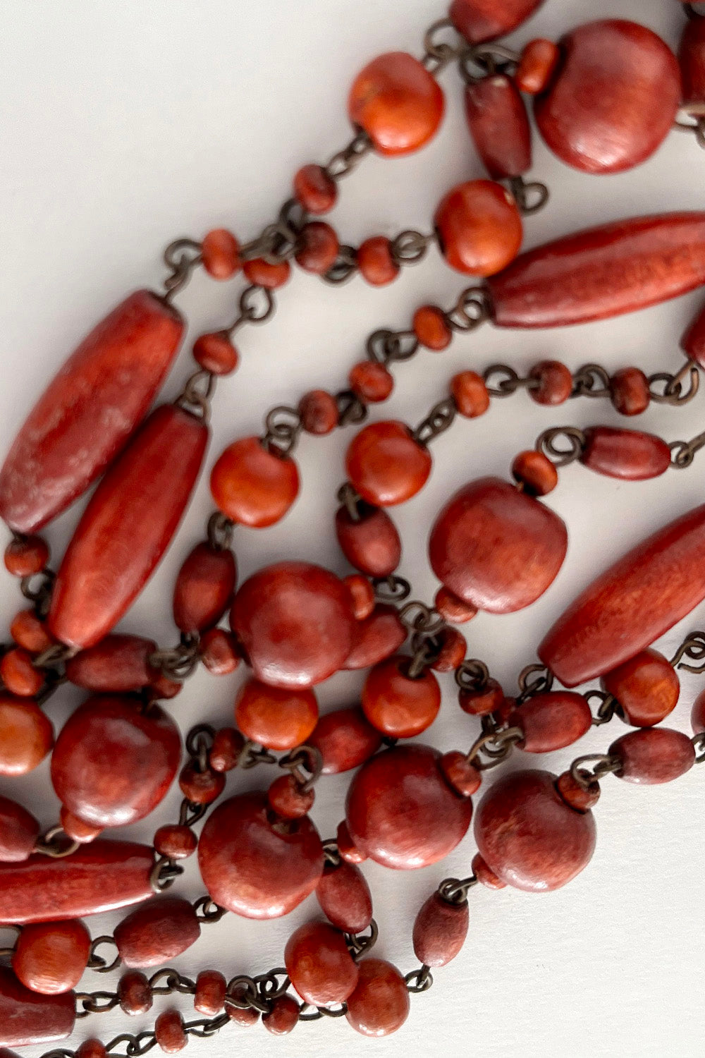 Vintage jaren 70 houten kralenketting rood-koper detail - close-up van houten en metalen kralen