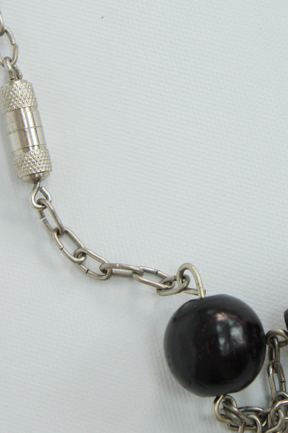 Vintage jaren 70 kralenketting zwart-donkerpaars detail kralen - close-up van zwarte en donkerpaarse kralen en zilverkleurig draaislotje