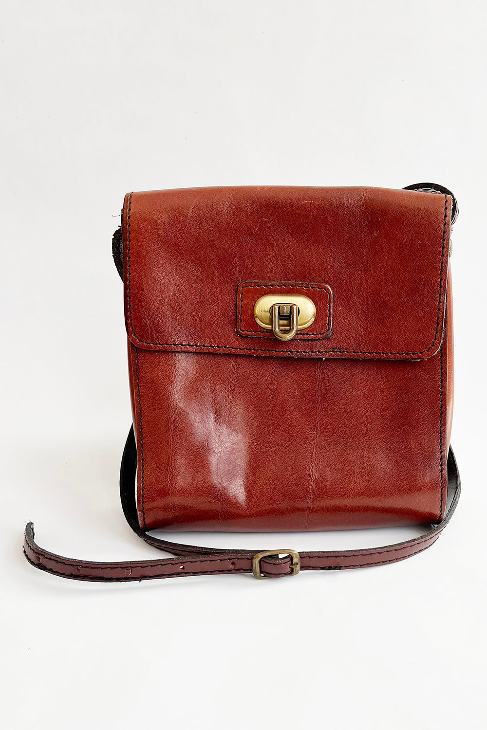 Vintage bruine leren schoudertas jaren 80 met gouden draaisluiting en verstelbaar hengsel – voorkant