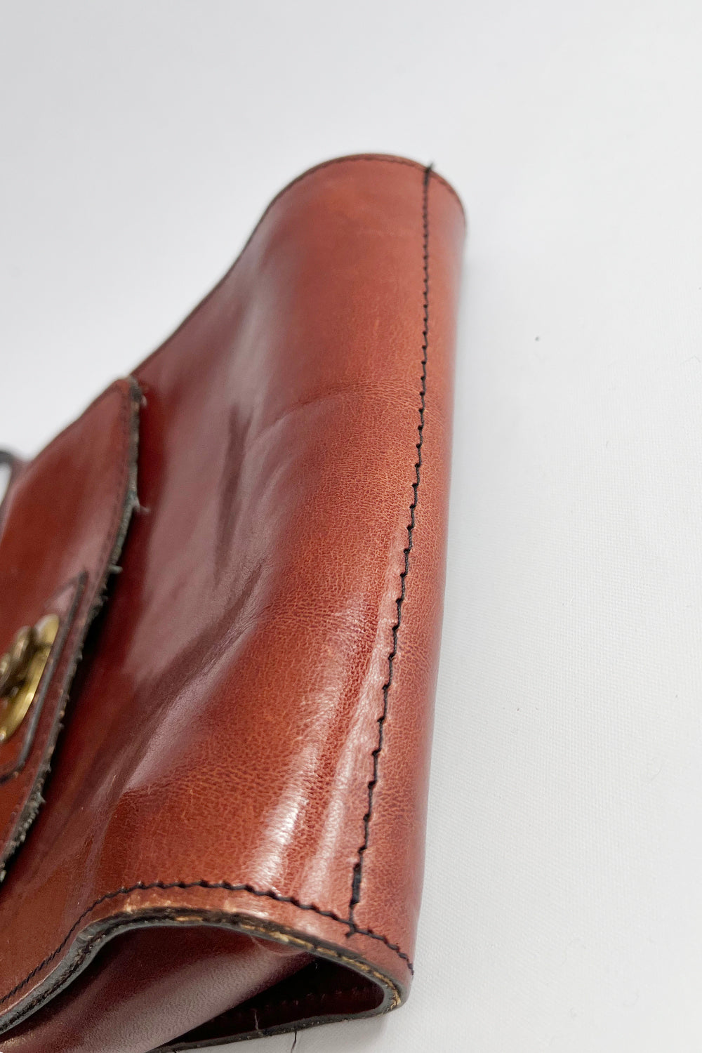 Detailopname zijkant vintage leren schoudertas – handgestikt leer met patina, bruinrood