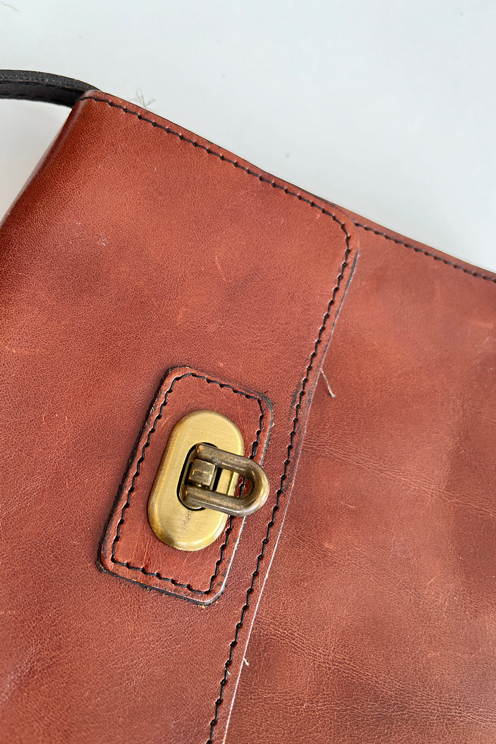Close-up gouden metalen draaisluiting vintage leren schoudertas – authentiek jaren 80 hardware detail