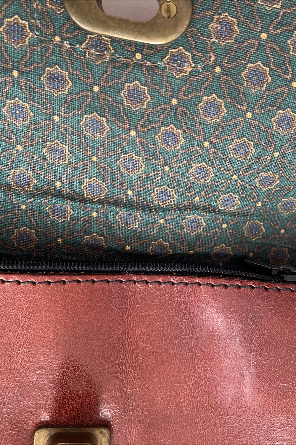 Detailopname groene bloemenprint voering vintage schoudertas – katoenen stof met gouden accenten en rits 