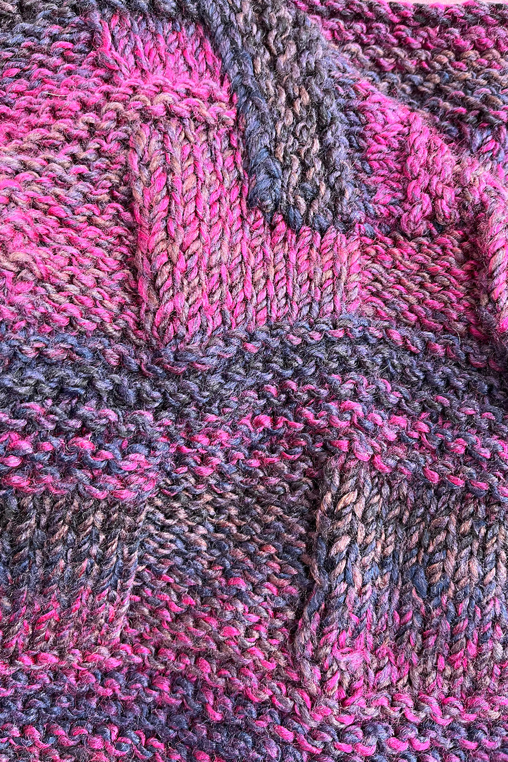 Detail van het blokvormige breipatroon van het vintage acrylvest in paars, felroze en donkerblauw.
