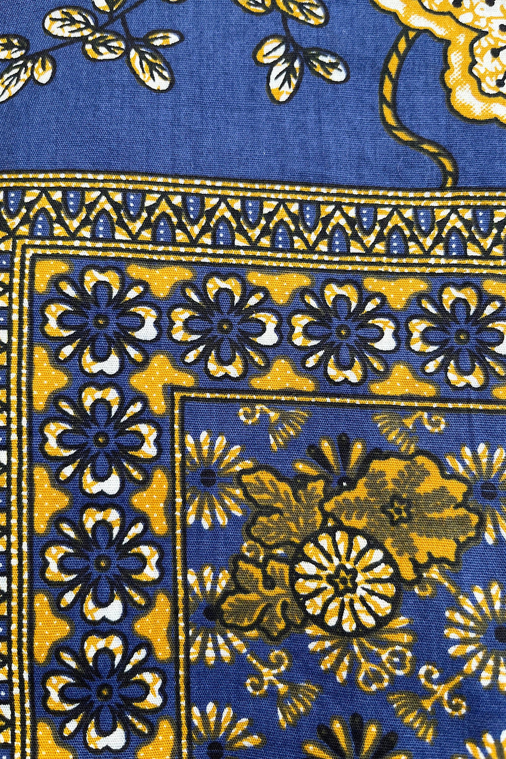 Vintage jaren 70 handgemaakte batik wikkelrok blauw-okergeel-zwart-wit detail - close-up van handbestempelde batik print