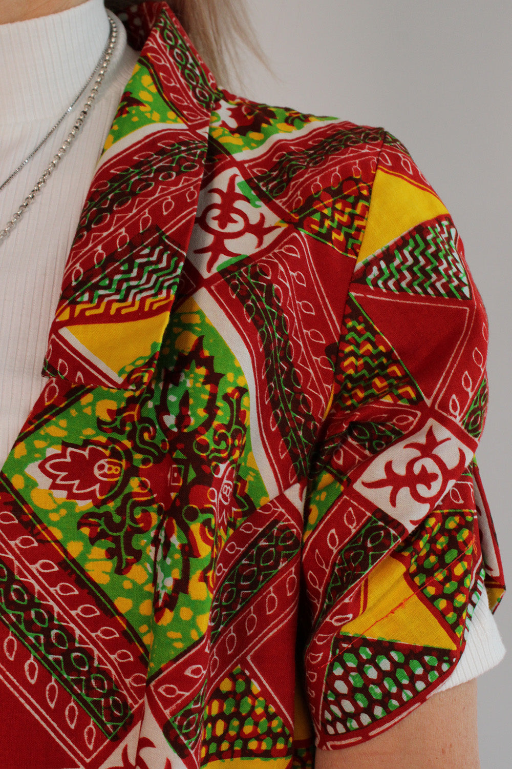 Vintage jaren 70 handgemaakte Afrikaanse batik peplum tuniek rood-groen-oranje-geel-wit detail kraag en mouw - close-up van stofstructuur