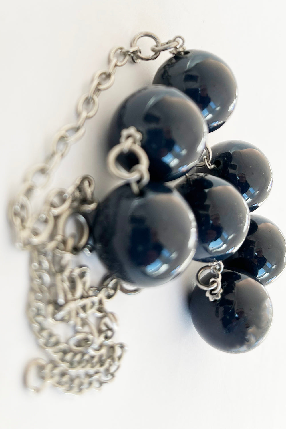 Vintage kralenketting donkerblauw-zilver detail - close-up van donkerblauwe plastic kralen en metalen sluiting
