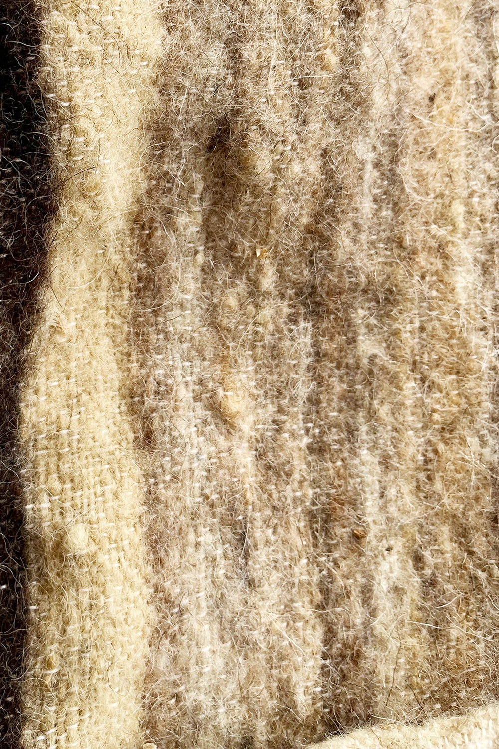 Detail van de harige wolstructuur en beige-crèmekleurige strepen van de vintage blanket coat.