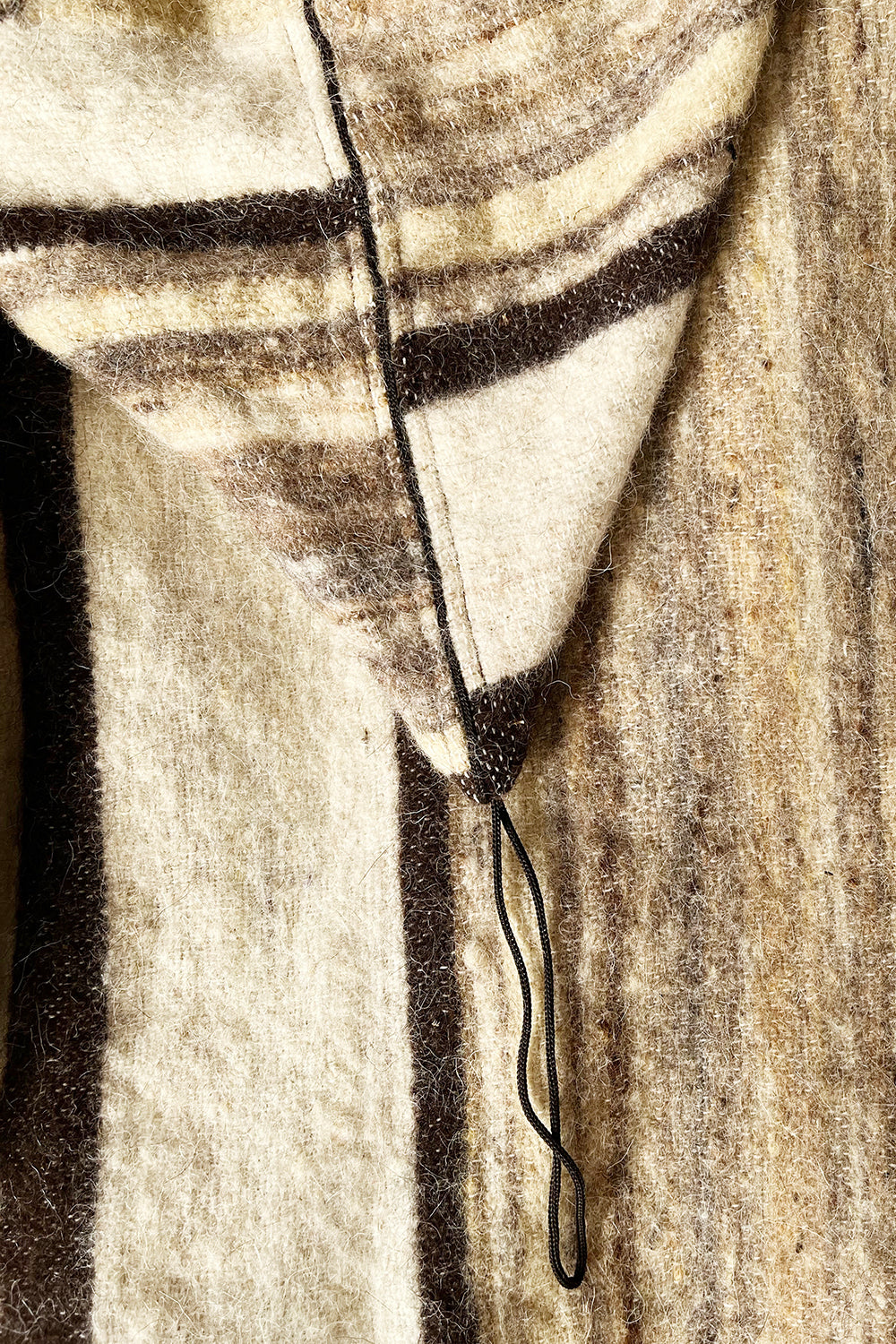 Detail van de gestreepte capuchon met zwarte randafwerking en koordje van de vintage wollen jas.